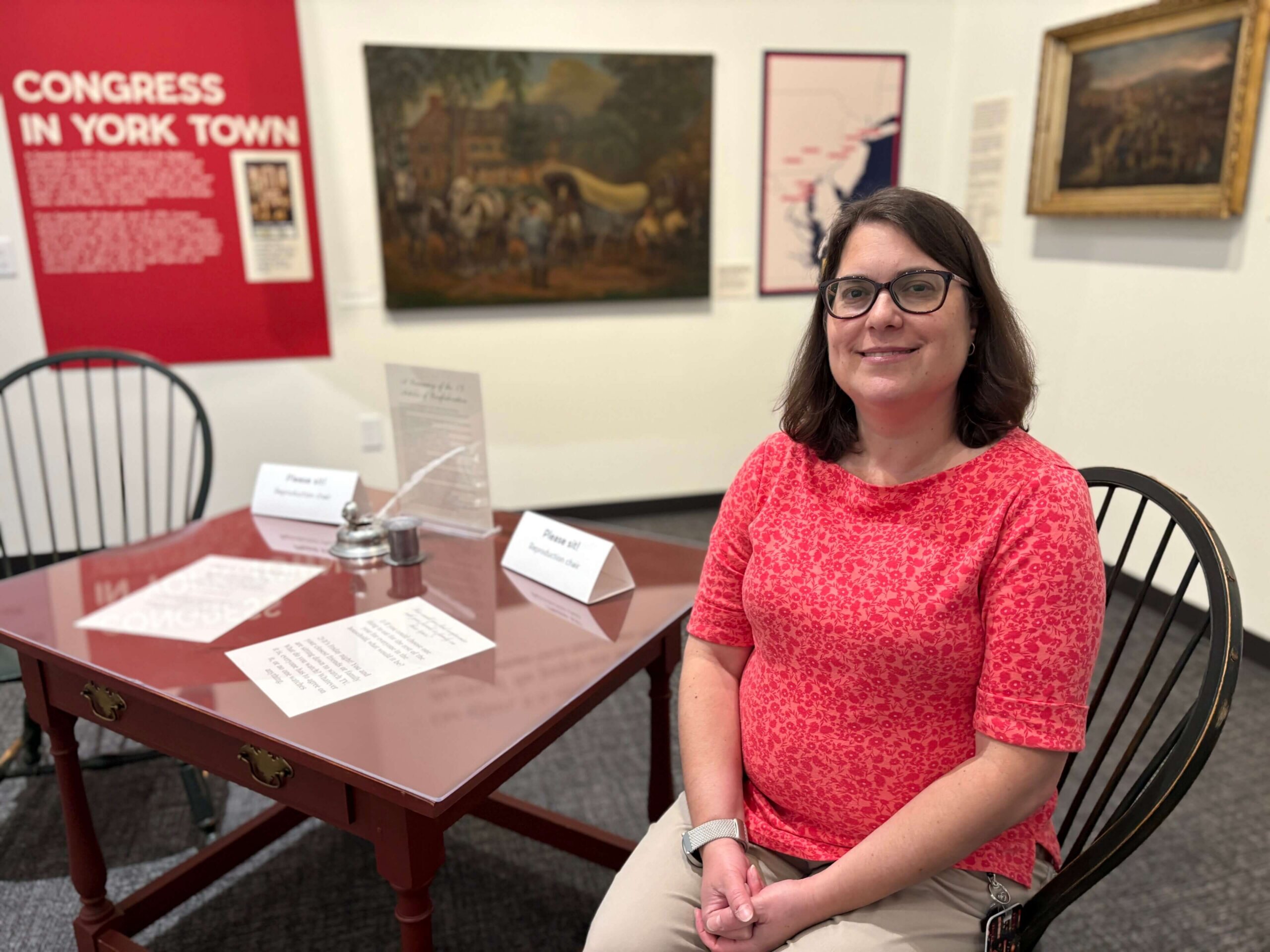 Nicole Smith, seated at a desk in the Revolutionary York exhibit