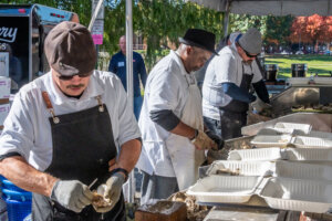 a row of three oyster shuckers wearing aprons and gloves