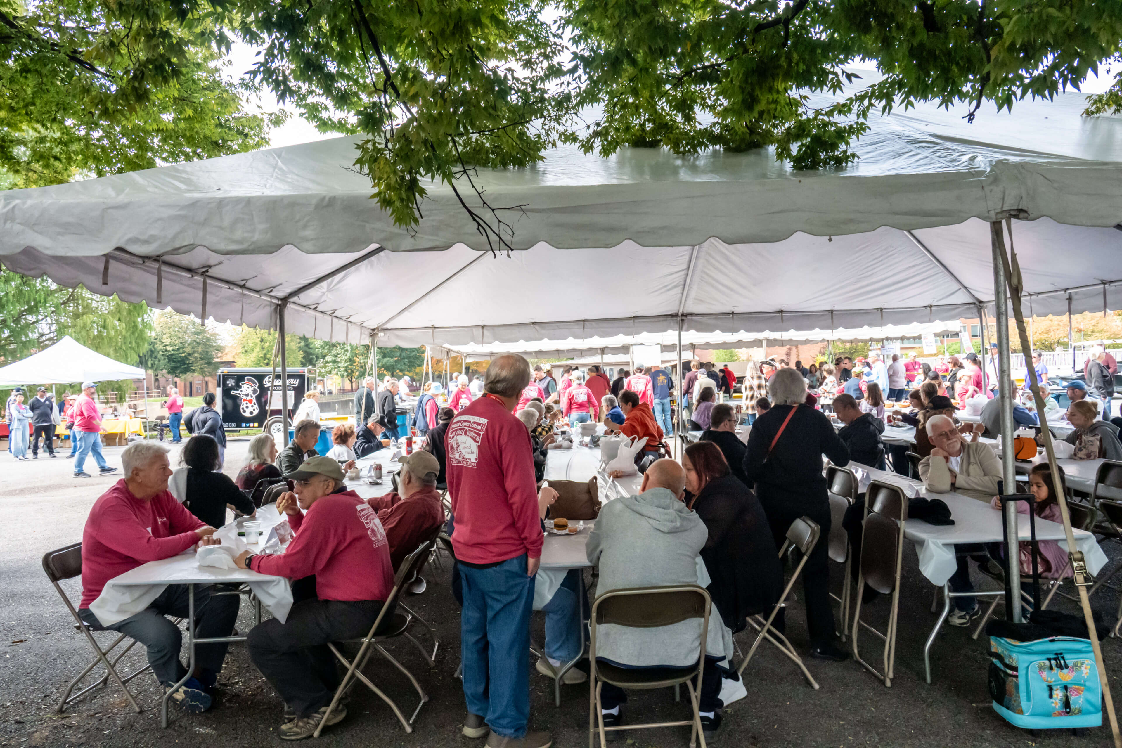 people seated at tables under a tent at the 2025 Oyster Festival